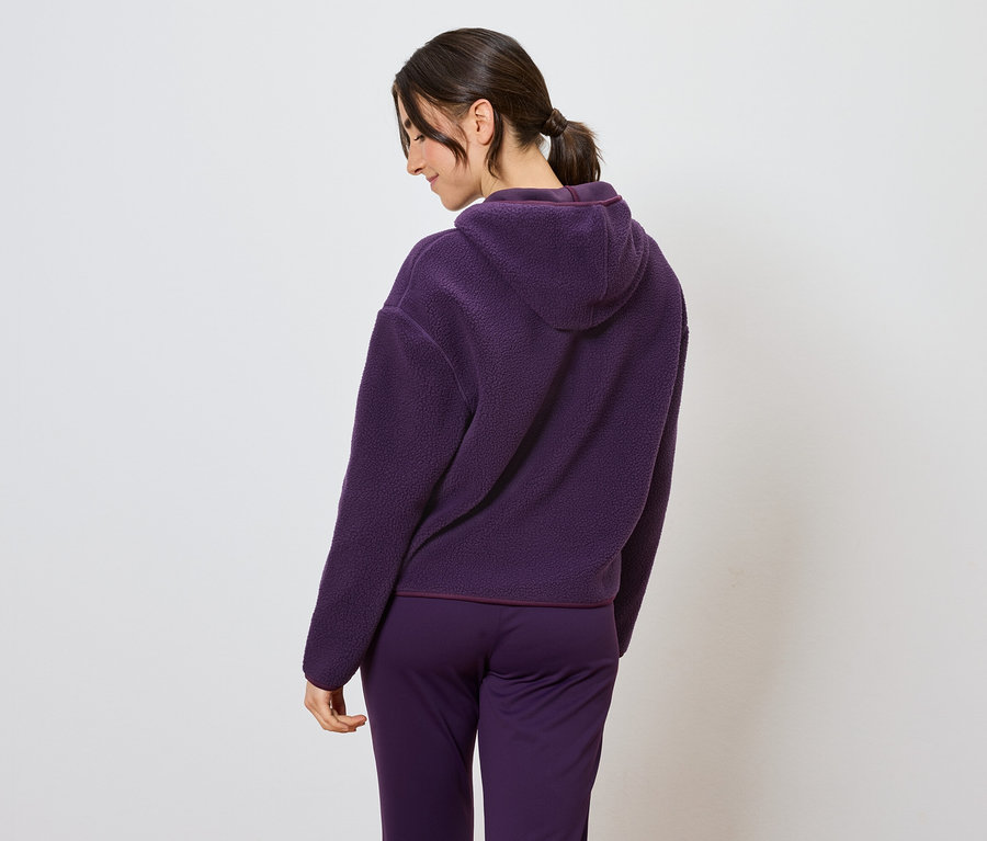 Arkadan görünüşüyle mor kapüşonlu eşofman takımı giyen kadın.