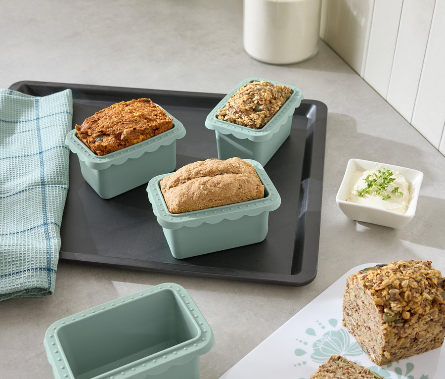 Mutfak masasında, fırın tepsisinde farklı ekmek çeşitleri bulunan mini pişirme kalıpları bulunmaktadır.