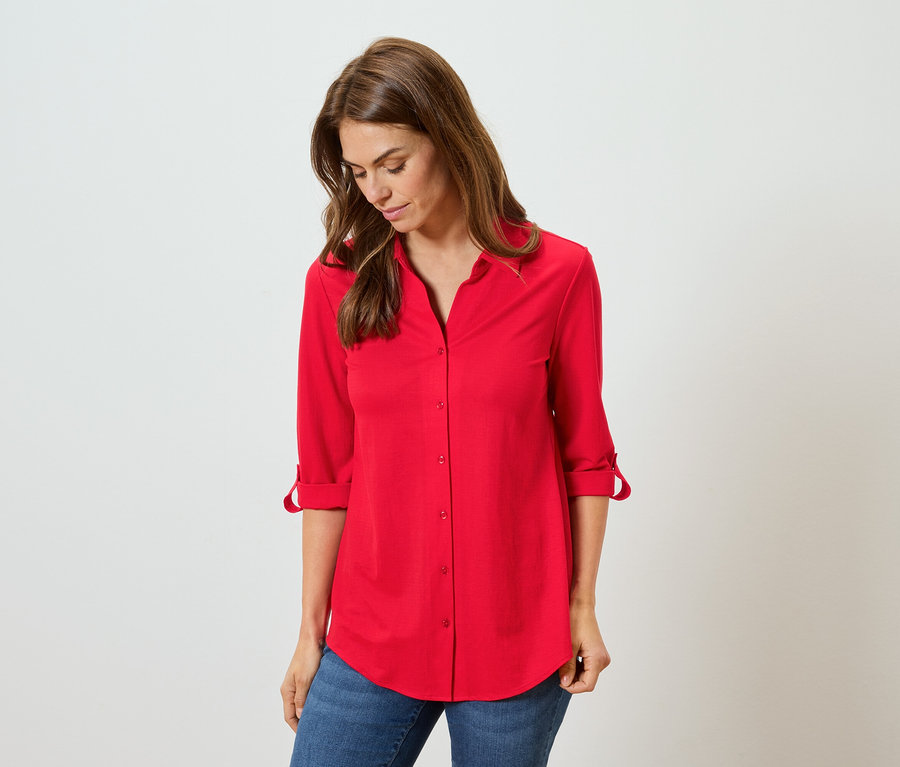 Kadın kırmızı gömlek ve mavi kot pantolon giyiyor.