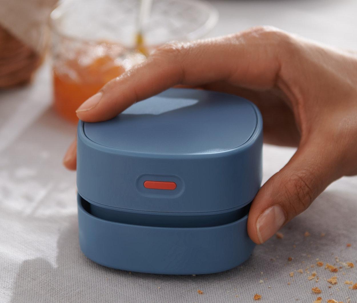 El, kırıntılı bir masanın üzerinde elektrikli mini masa süpürgesi tutuyor.