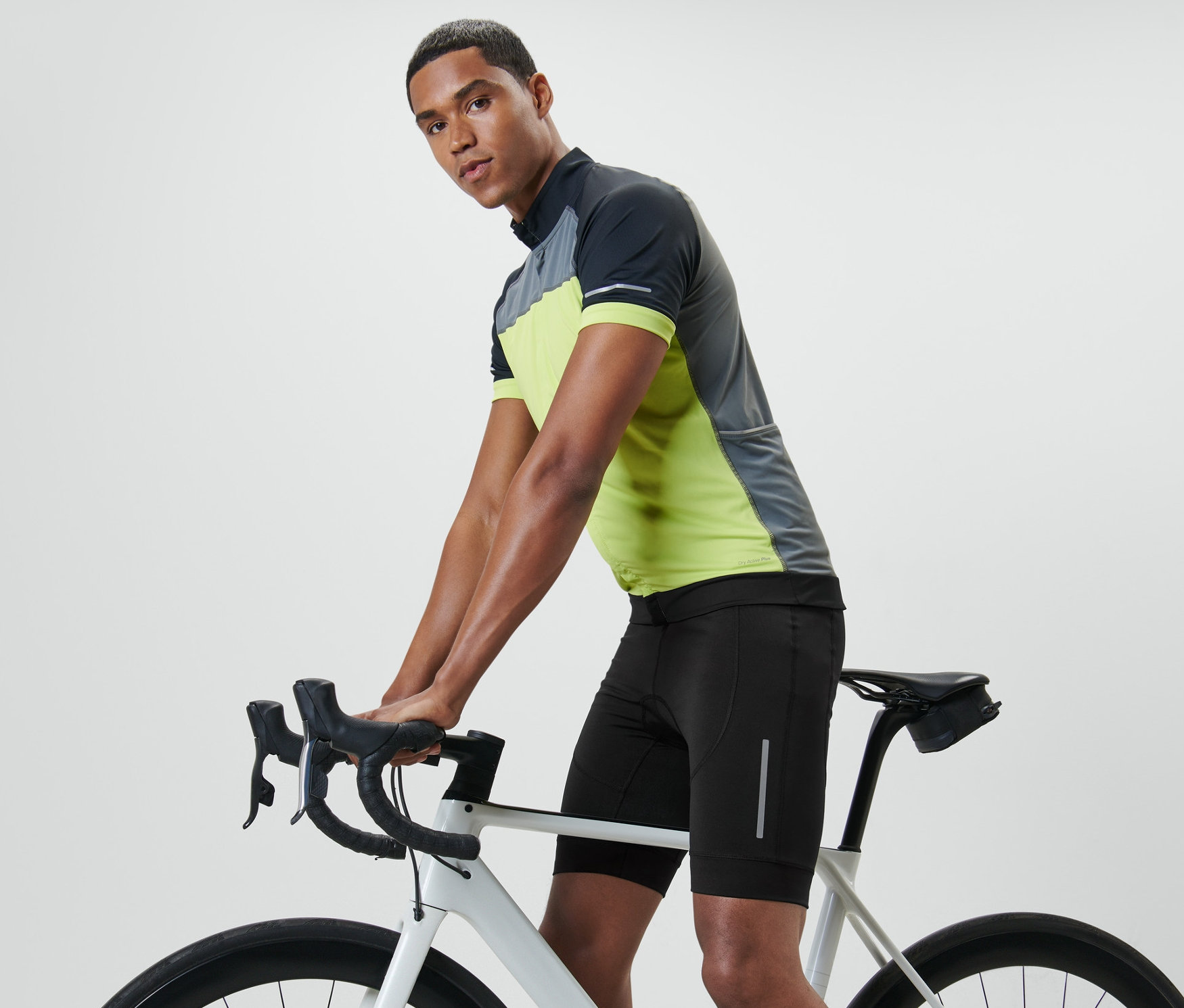 Bisiklet gidonuna yaslanan adam bir bisiklet taytı giyiyor.