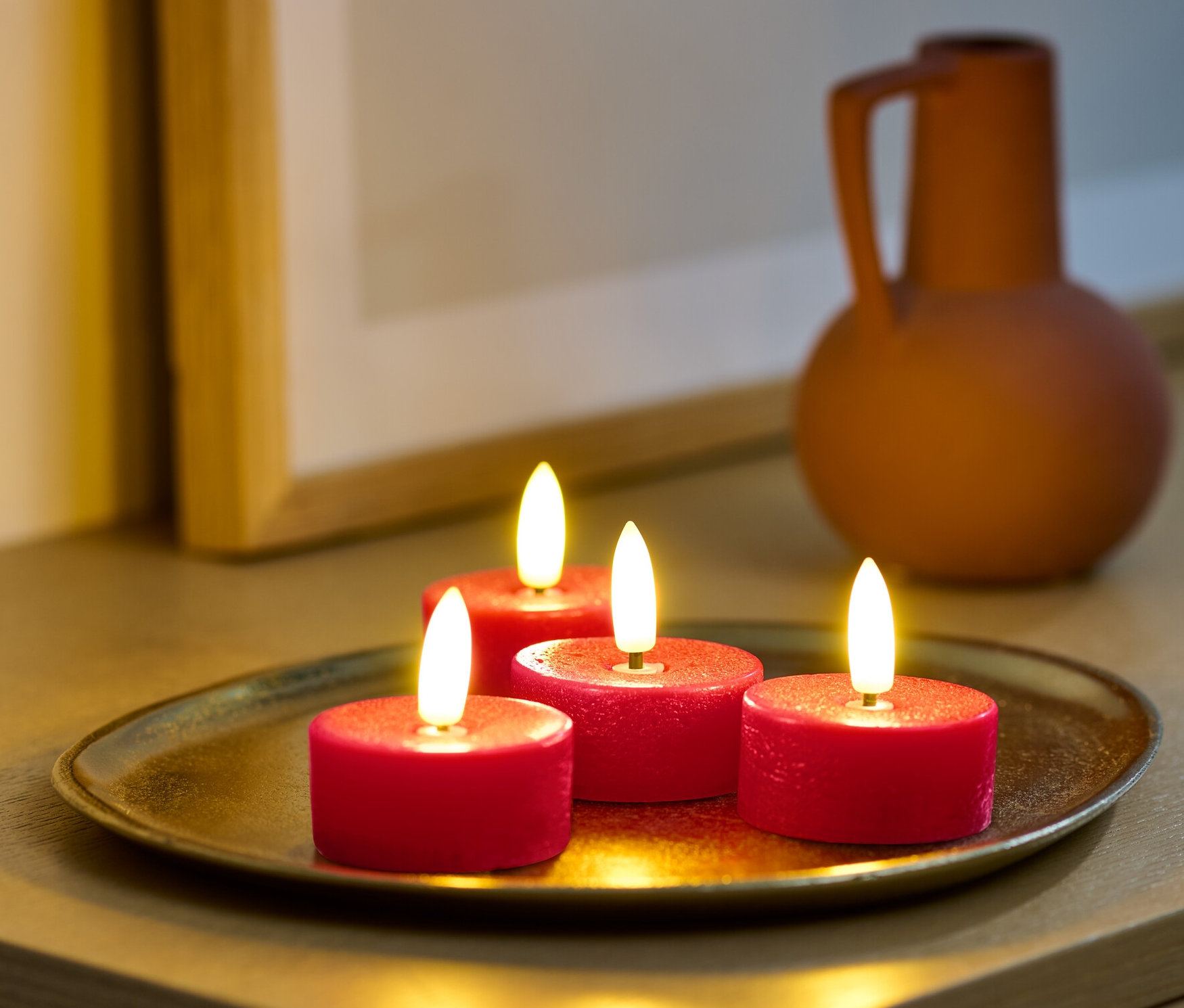 Bir dolap üzerinde altın bir tepside dört adet kırmızı LED gerçek mum tealight.