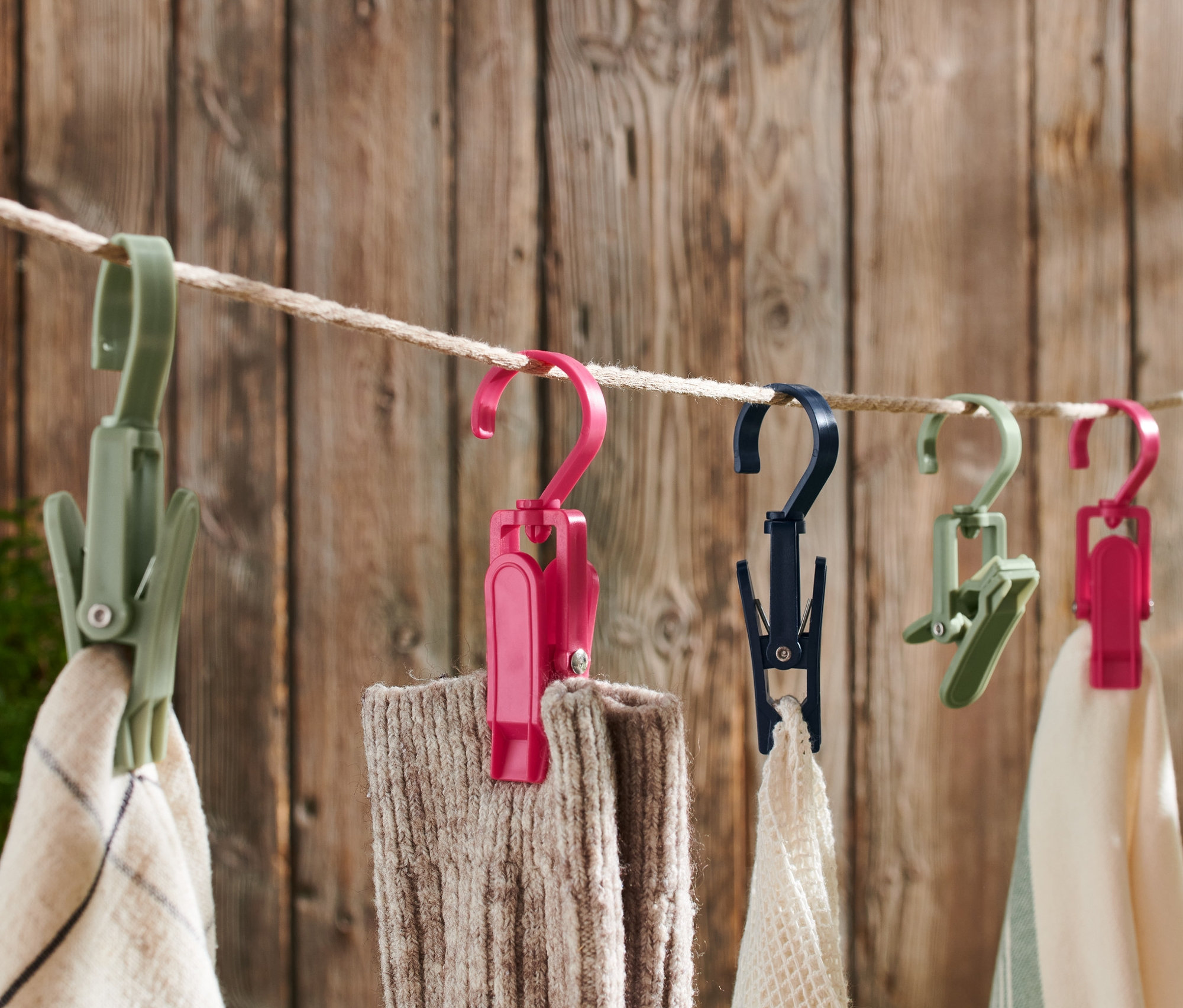 Çeşitli renklerde 6 Adet Outdoor Klips bir ipe asılı duruyor ve kumaşı tutuyor.