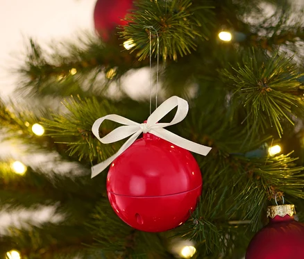 Kırmızı şarkı söyleyen bir Noel küresi, diğer kırmızı küreler ve ışıklarla birlikte bir Noel ağacında asılı duruyor.