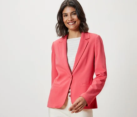 Gülümseyen kadın, mercan rengi Jersey Blazer Ceket giyiyor.