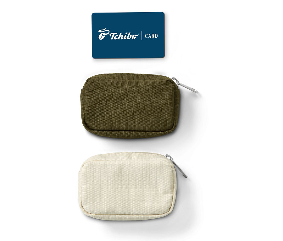 Mavi bir Tchibo kartı, biri zeytin yeşili, diğeri krem rengi olmak üzere iki adet mini seyahat düzenleme çantasının üzerinde.