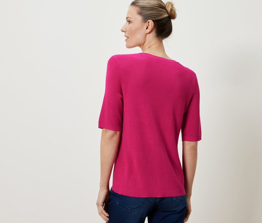 Kadın üzerinde pembe, ince örgü ketenli hırka var.