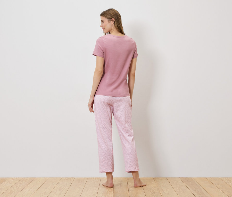 Uzun saçlı bir kadının pembe bir tişört ve geometrik desenli pembe bir pijama altı giydiği arka görünümü.