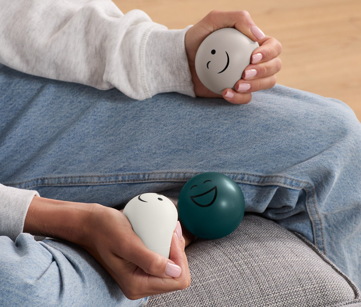 Kadın kanepede oturuyor ve ellerinde 3 adet stres topu tutuyor.