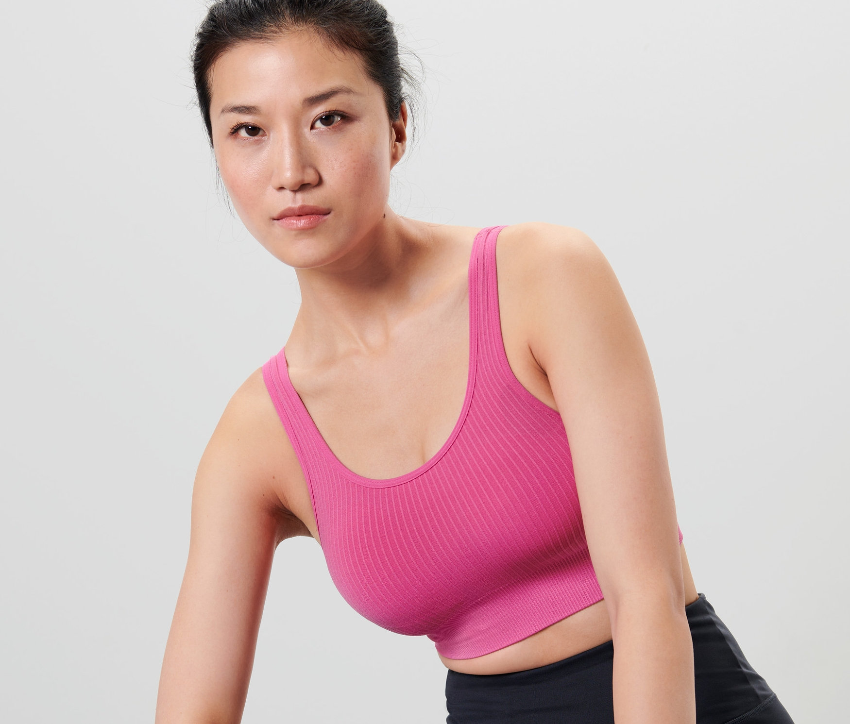 Asyalı kadın Dikişsiz Spor Büstiyer, siyah spor şortu ve mor bir ter bandı takıyor.