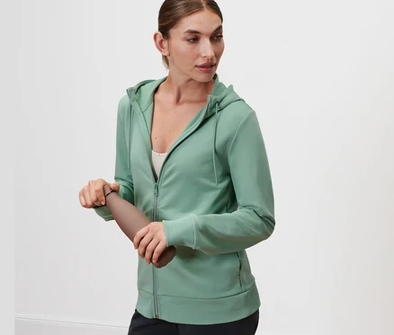 Kadın kahverengi bir su şişesi tutuyor ve Ada Çayı Yeşili renginde bir Sweat Ceket giyiyor.