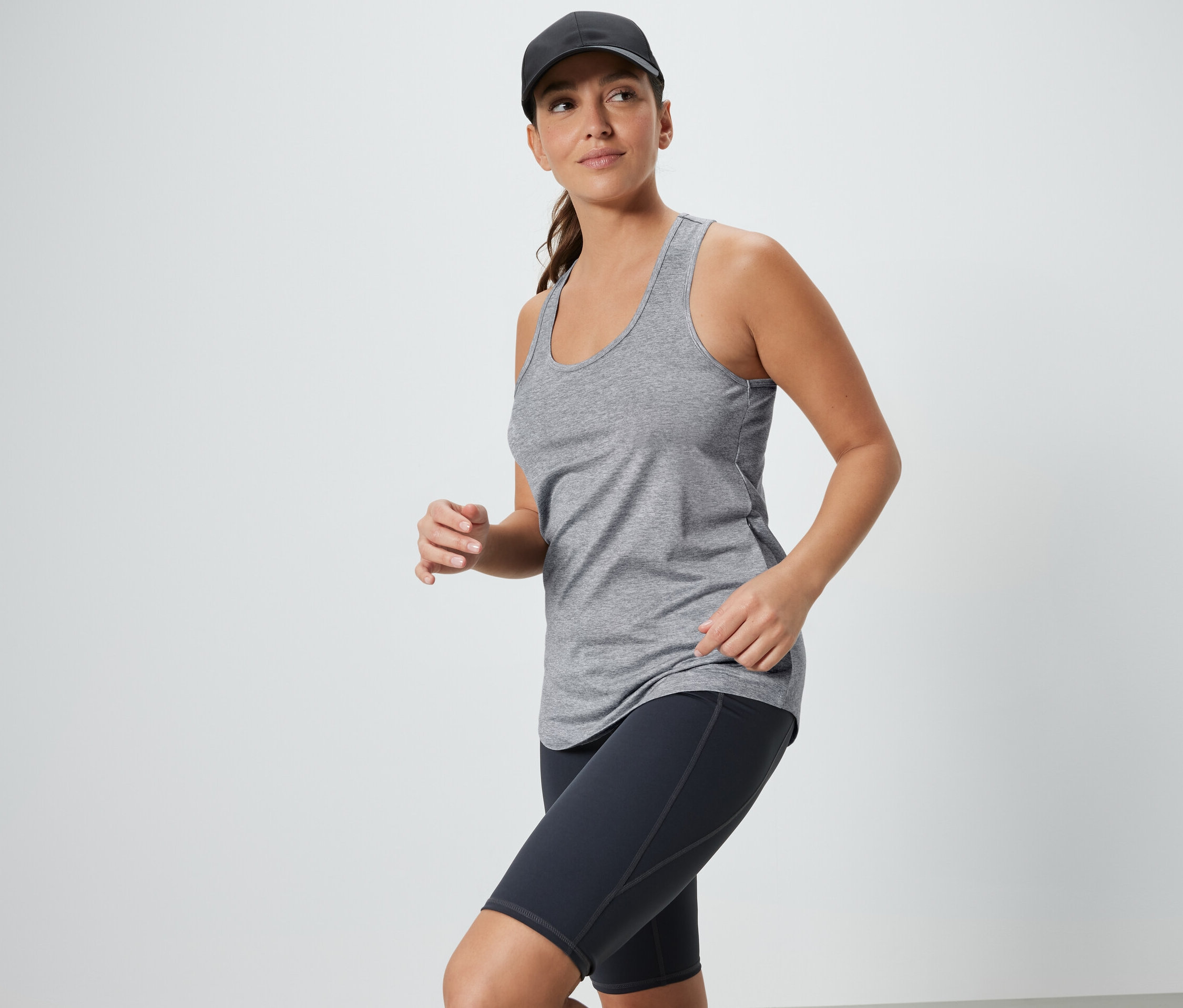 Kadın gri atlet ve siyah spor şortu ve şapka takıyor. 2 Adet Fonksiyonel Atlet, Siyah ve Gri.