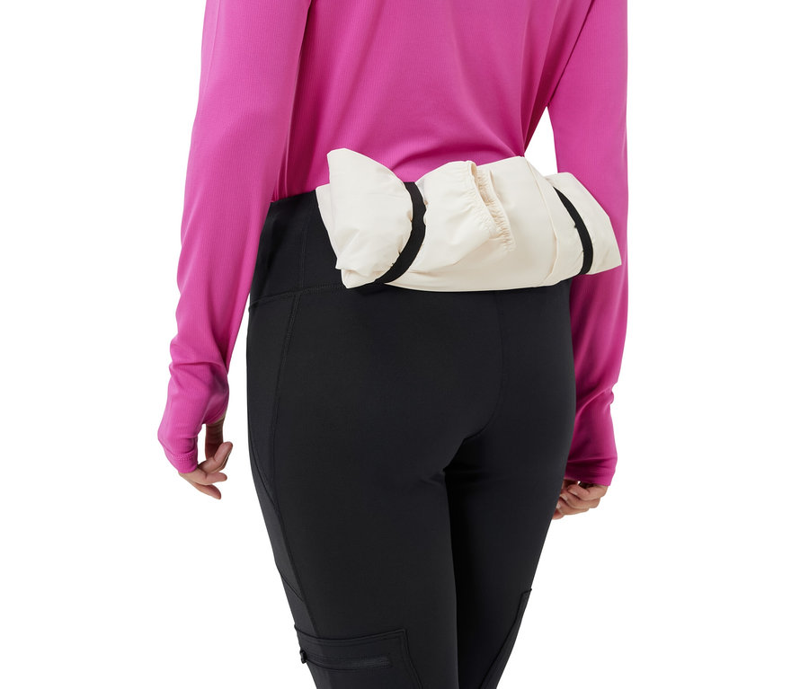 Kadın, siyah outdoor taytı ve belinde krem rengi bir ceket giyiyor.