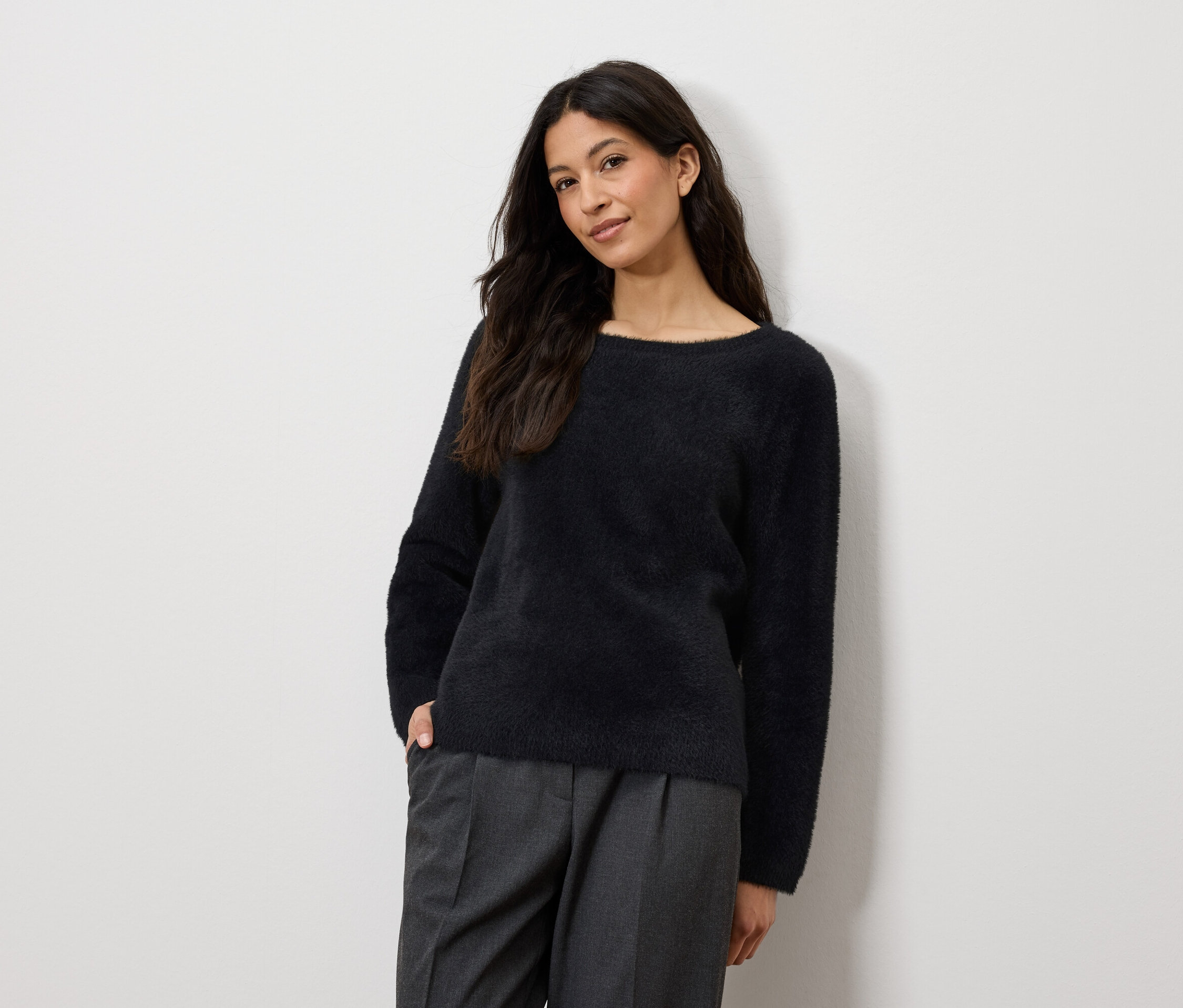 Lacivert kazak ve gri pantolonlu bir kadın poz veriyor.