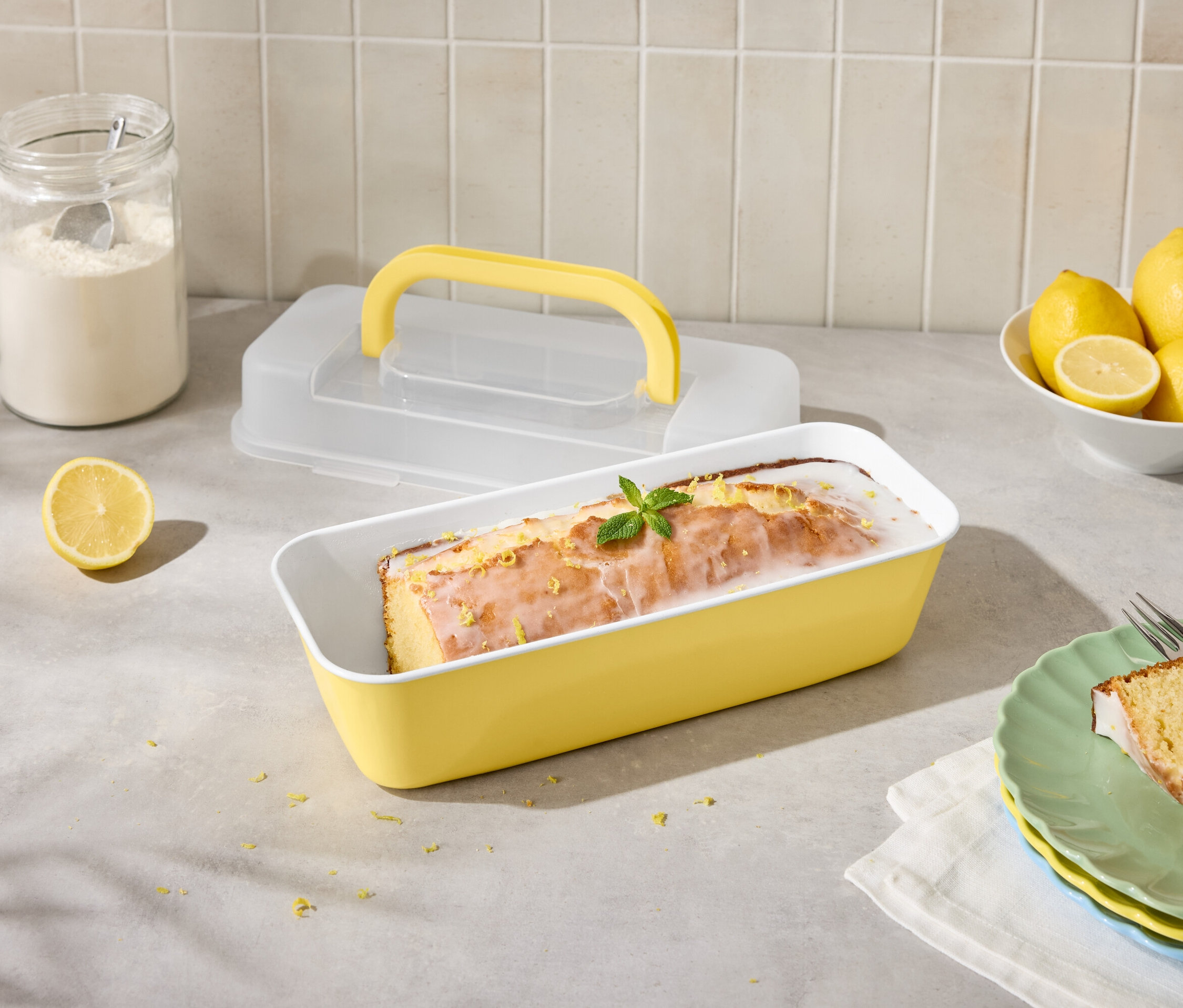 Limonlu kek, limon ve şekerlemeli sarı kalıpta, çatalla birlikte dilimlenmiş olarak tabakta.