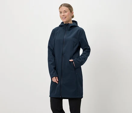 Kapüşonlu ve fermuarlı, lacivert, uzun softshell montlu, eli cebinde bir kadın.