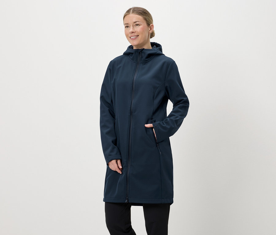 Kapüşonlu ve fermuarlı, lacivert, uzun softshell montlu, eli cebinde bir kadın.