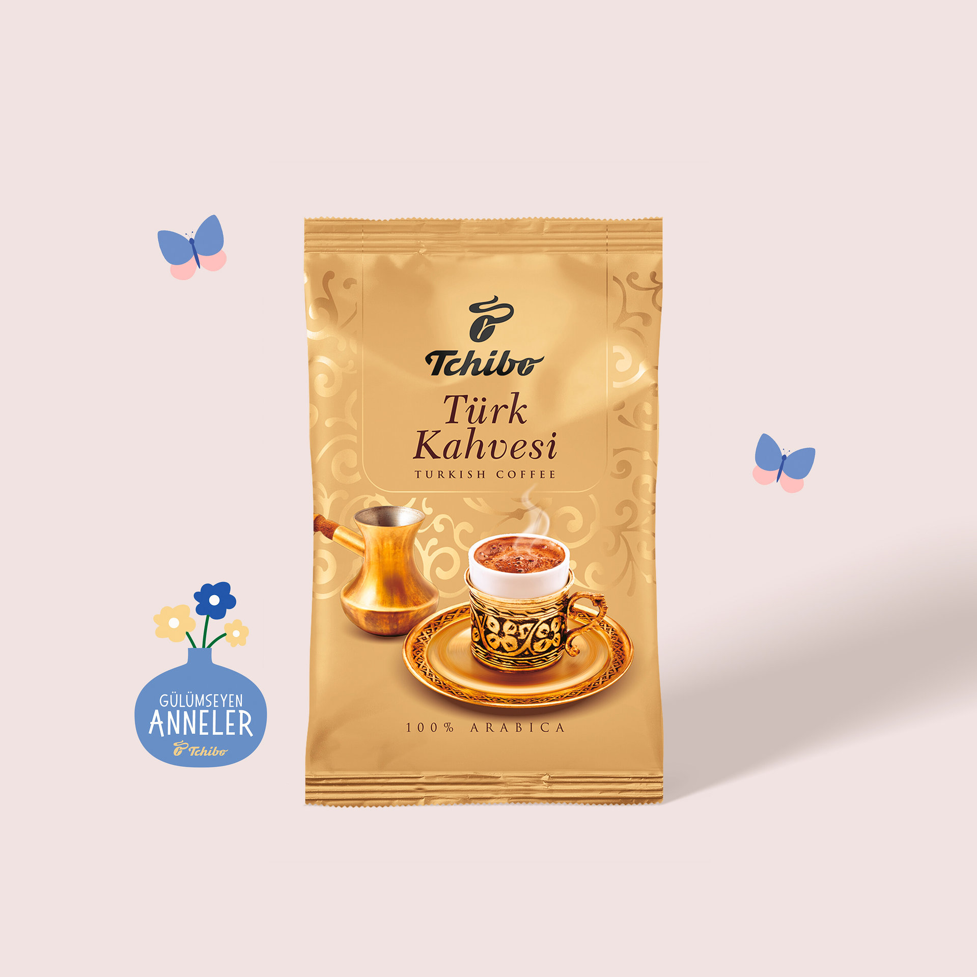 Bakır cezve ve buharlı, süslü altın bir fincan kahve illüstrasyonu içeren altın rengi Tchibo Türk Kahvesi paketi. Paketin üzerinde "100% ARABICA" yazısı bulunuyor. Arka planda iki mavi kelebek ve çiçekli mavi bir vazo var.