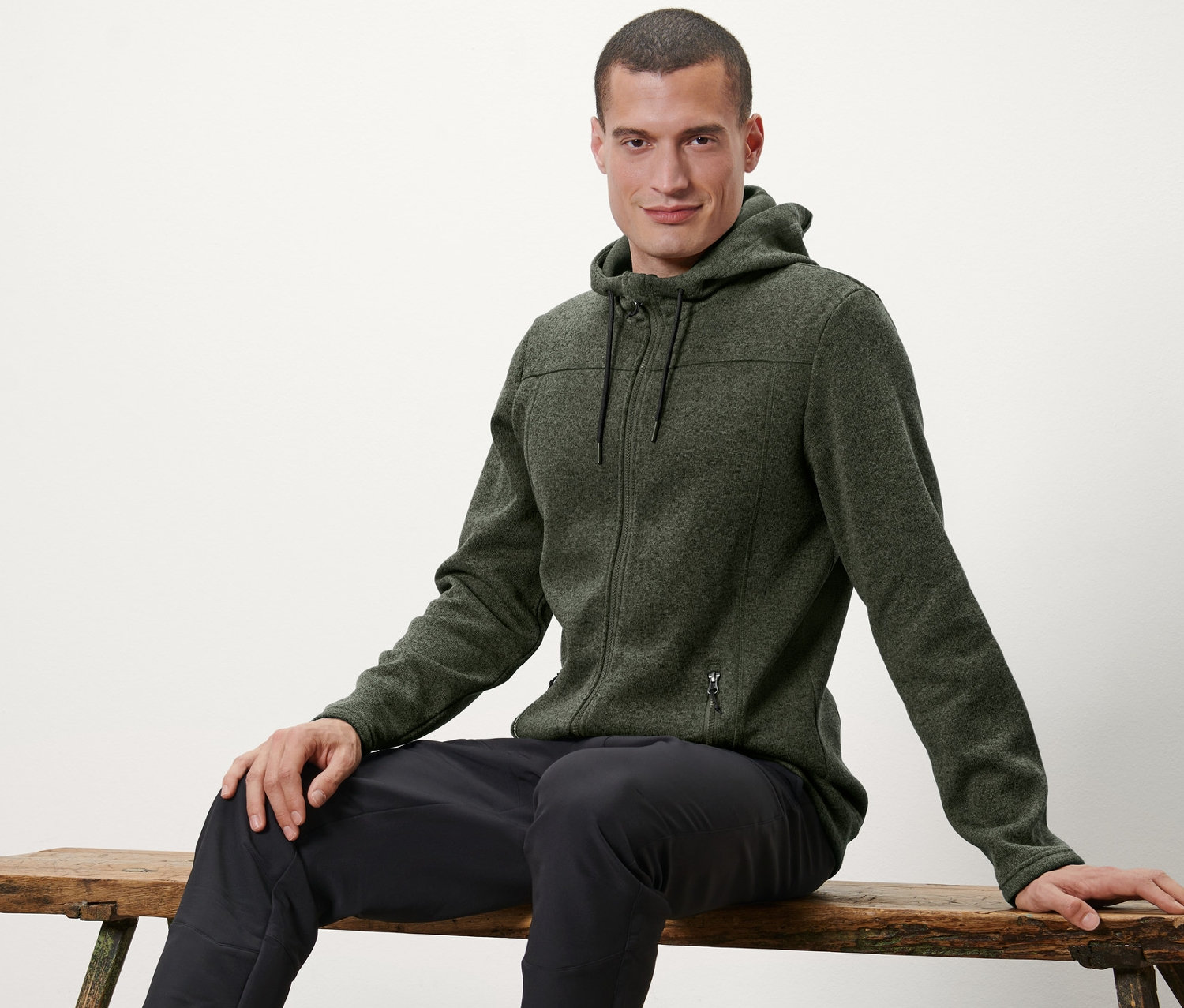 Adam bankta oturuyor ve Örgü Polar Ceket giyiyor.