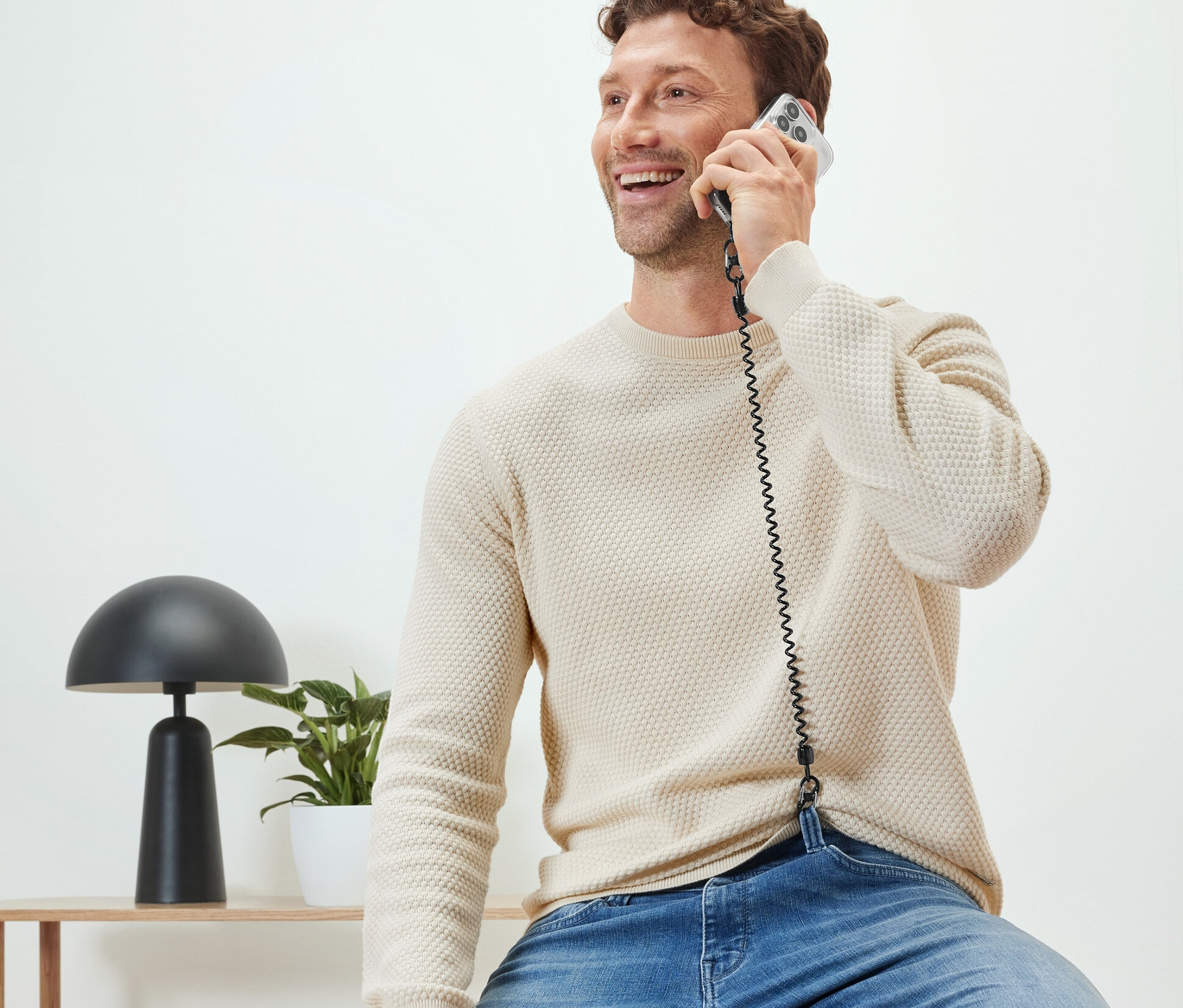 Adam oturmuş, Güvenli Cep Telefonu Zinciri ile telefonda konuşuyor.