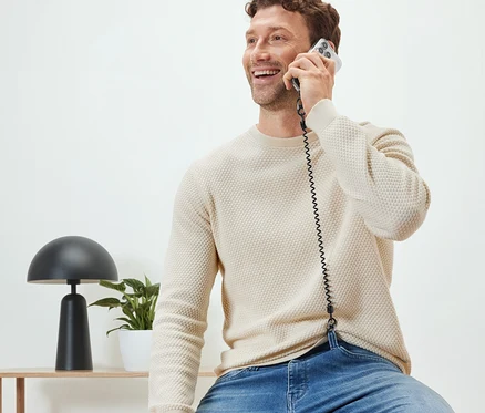Adam oturmuş, Güvenli Cep Telefonu Zinciri ile telefonda konuşuyor.