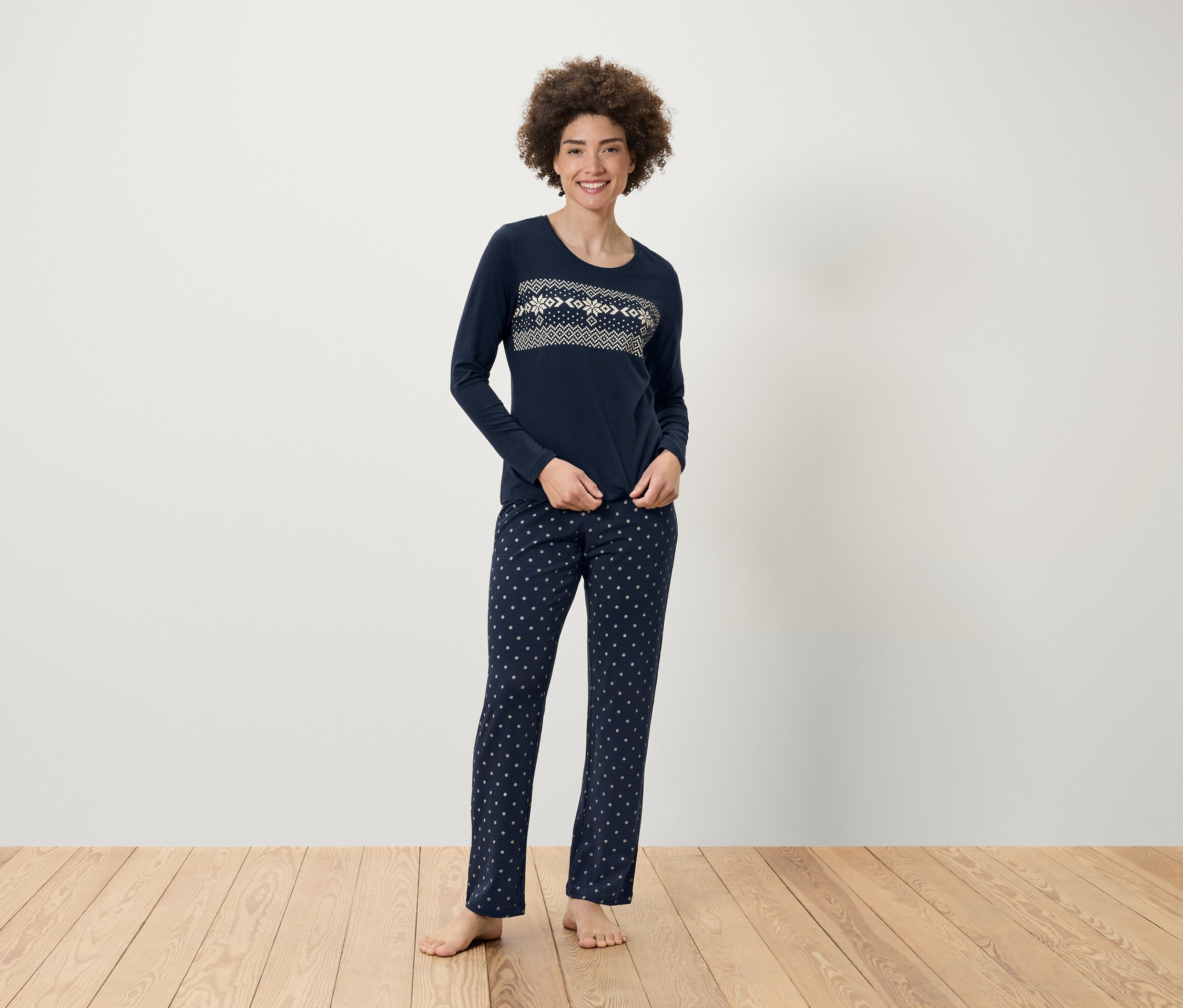 Kadın desenli, lacivert pijamasıyla ayakta duruyor.