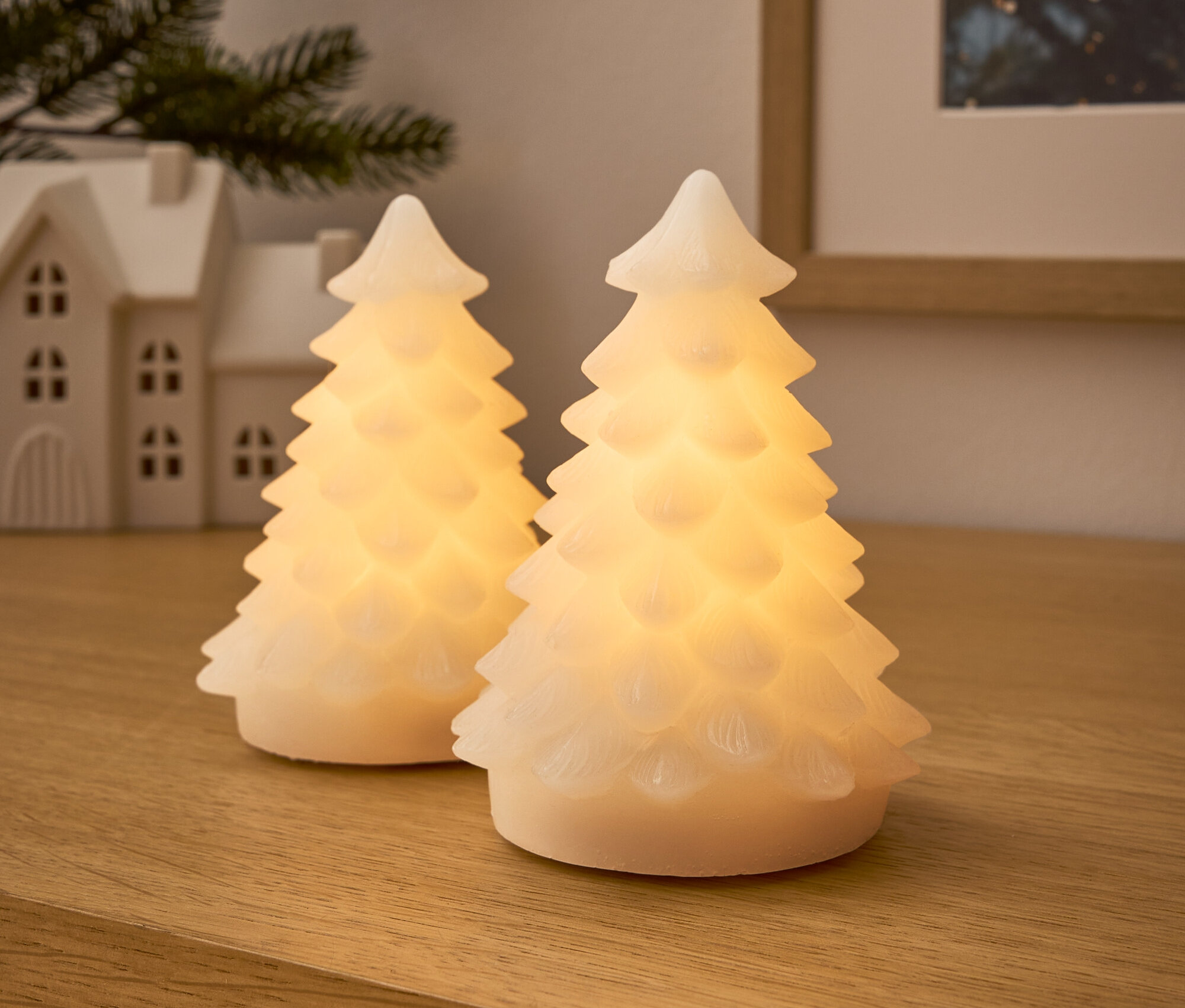 Ahşap bir yüzeyde iki adet ışıklı ağaç.