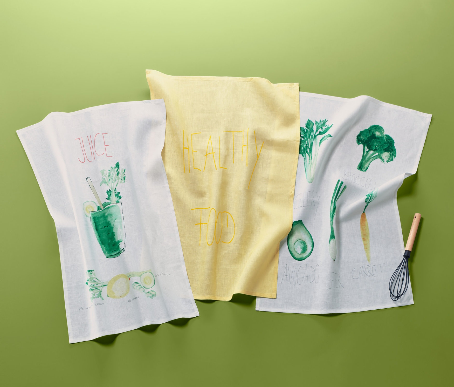 Yeşil zemin üzerinde sebze baskılı üç adet keten kurulama bezi.