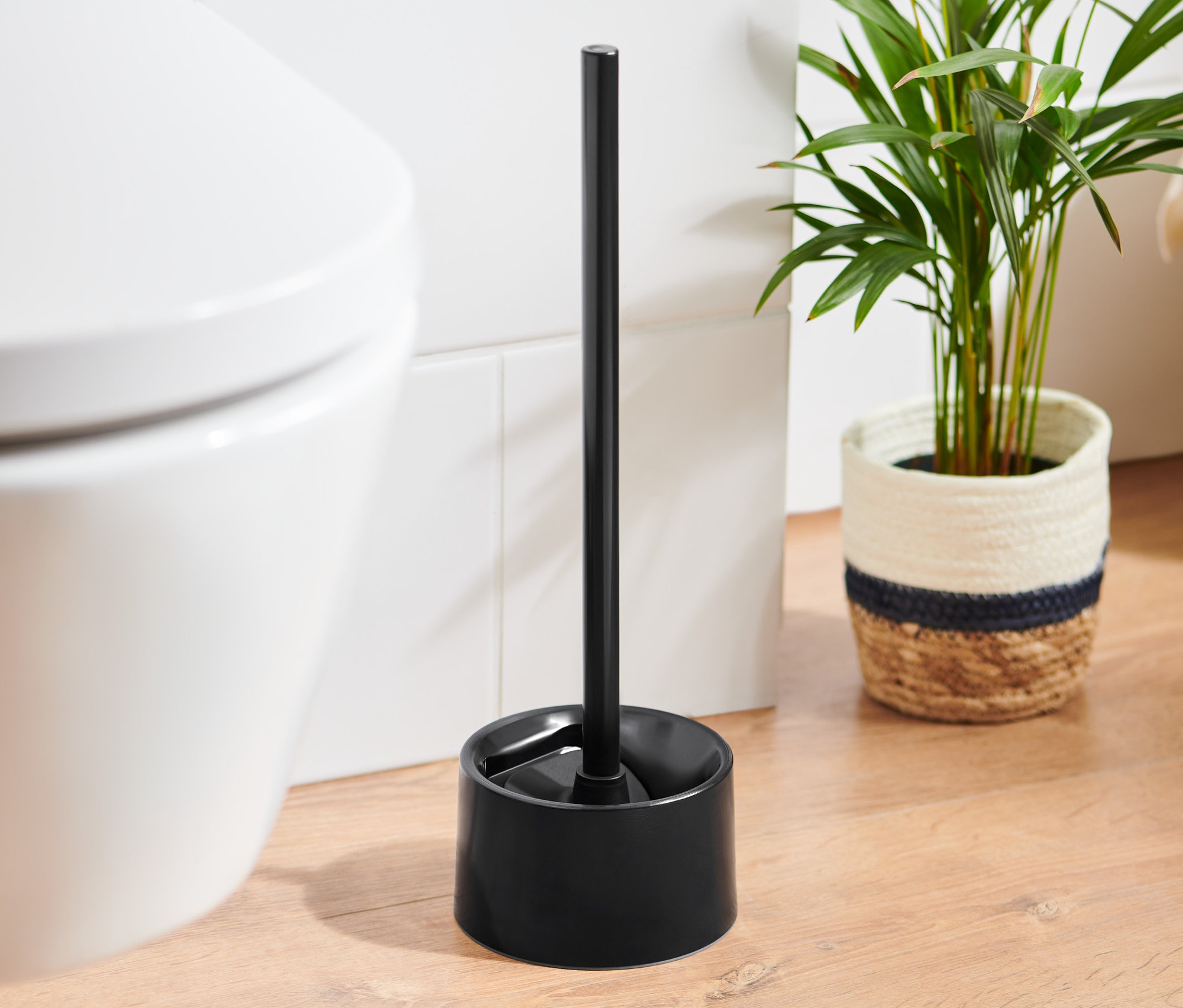 Siyah silikon tuvalet fırçası, beyaz bir tuvaletin yanında duruyor.