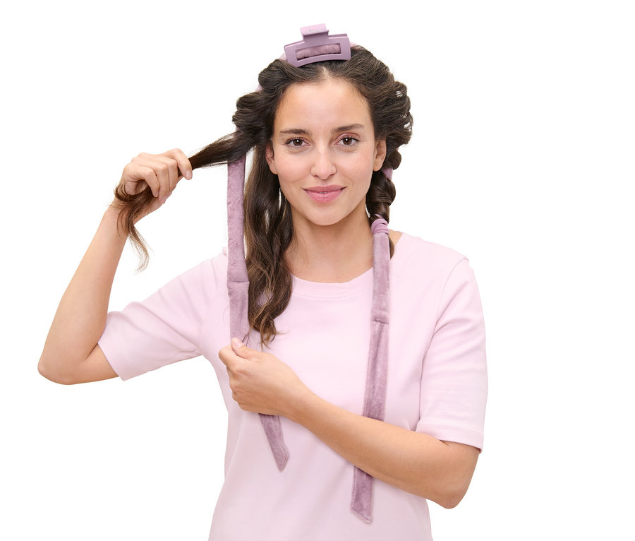 Kadın ısısız bigudi ile saçını sarıyor.
