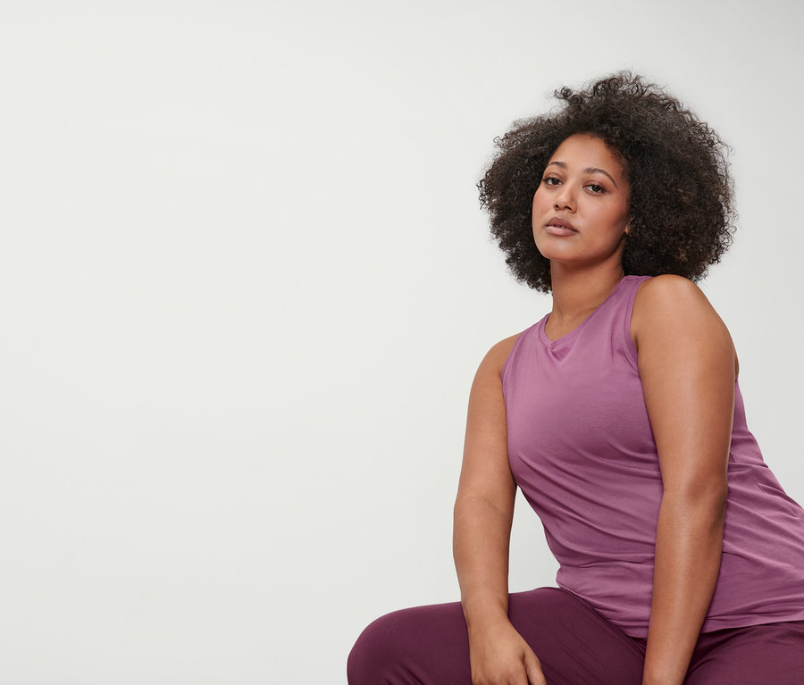Kadın mürdüm rengi 3/4 yoga pantolonu ve eflatun spor üst giyiyor.