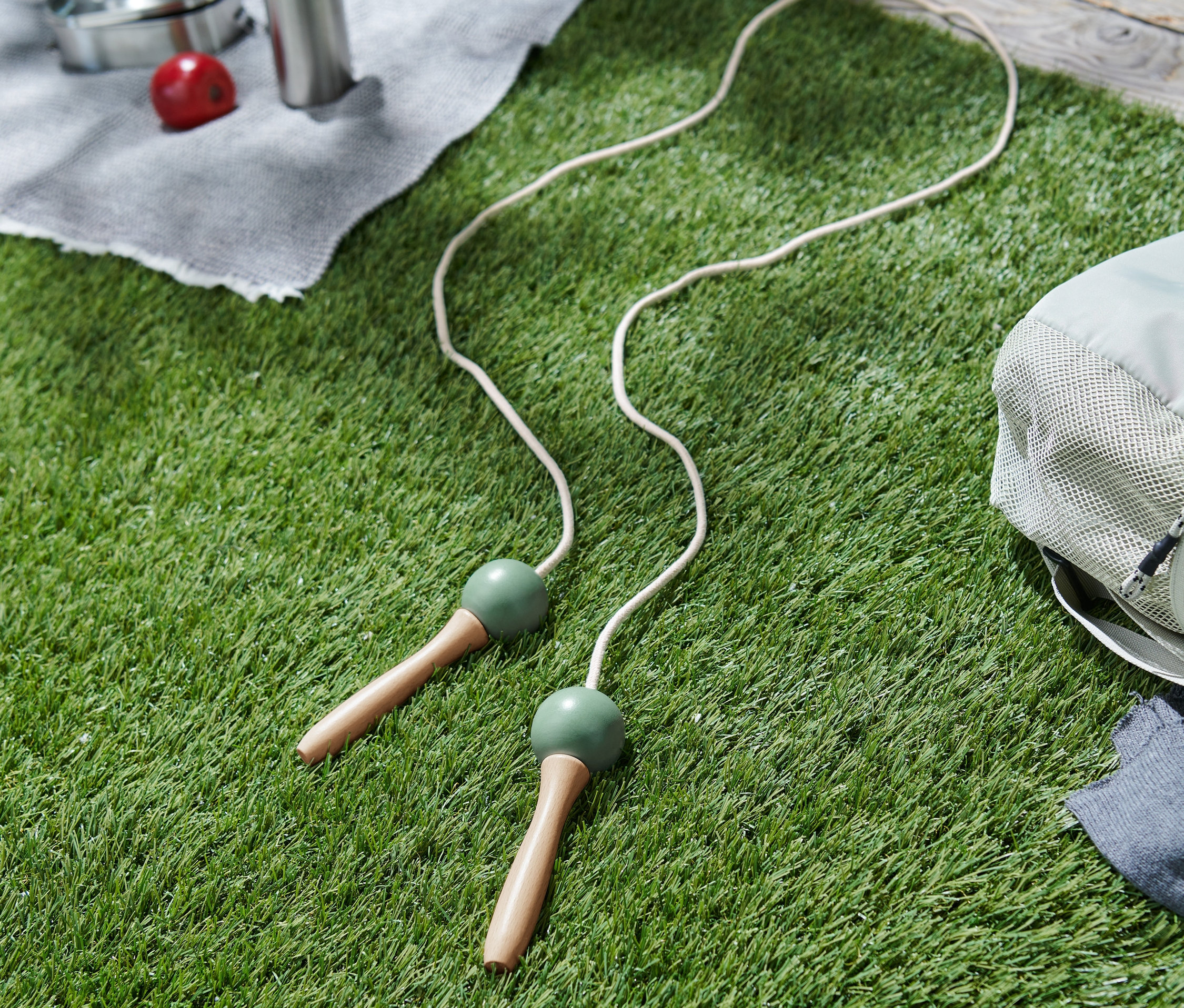 Beyaz atlama ipi, bir sırt çantasının yanında çimenlerin üzerinde duruyor.