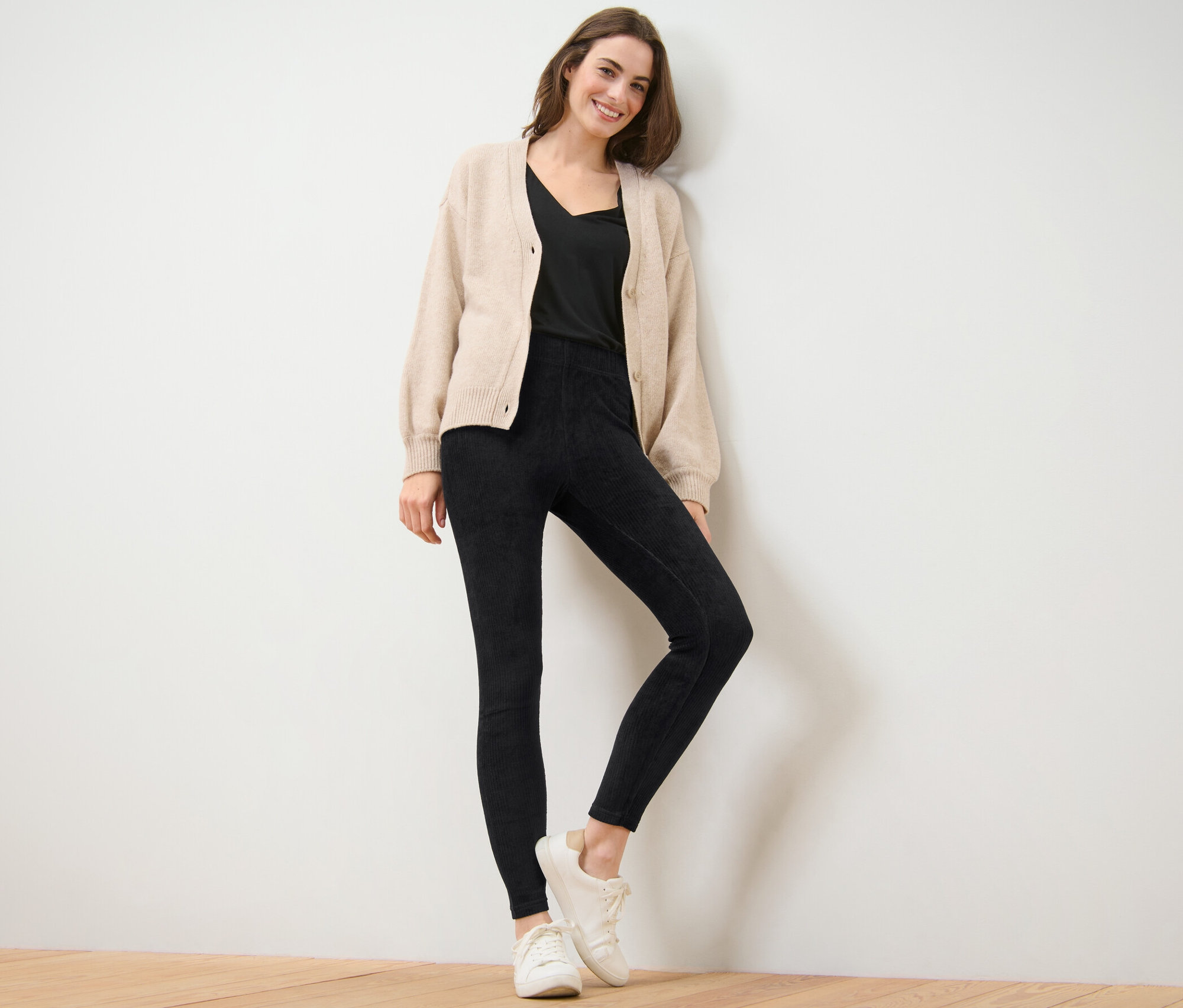 Kadın siyah kadife taytla poz veriyor.