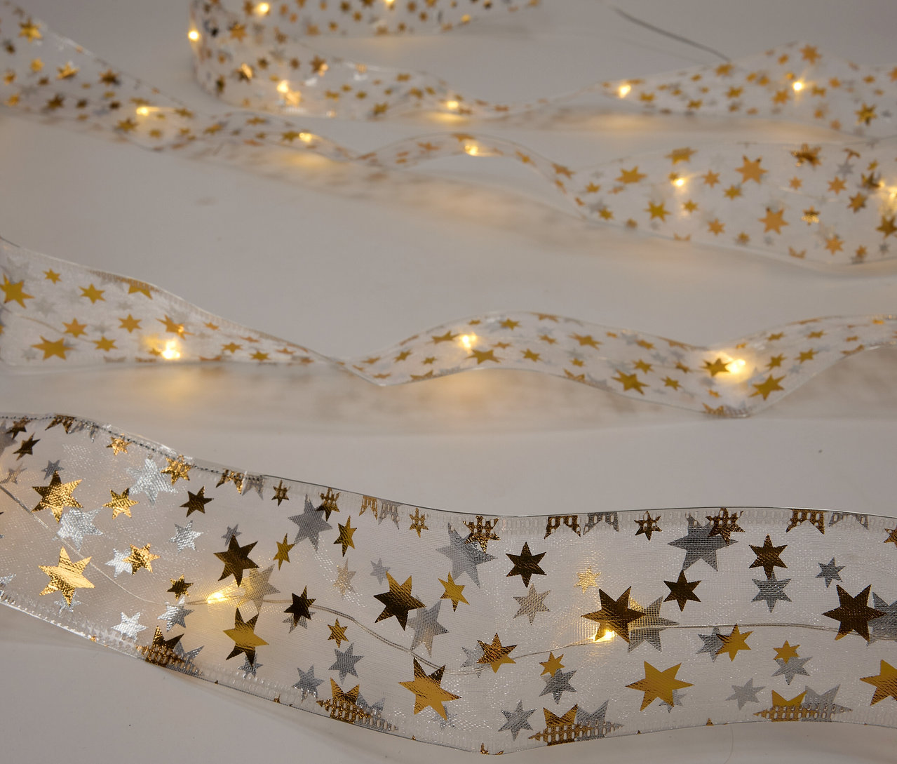 Beyaz bir arka plan üzerinde LED ışıkları ve yıldızları olan üç kurdele.