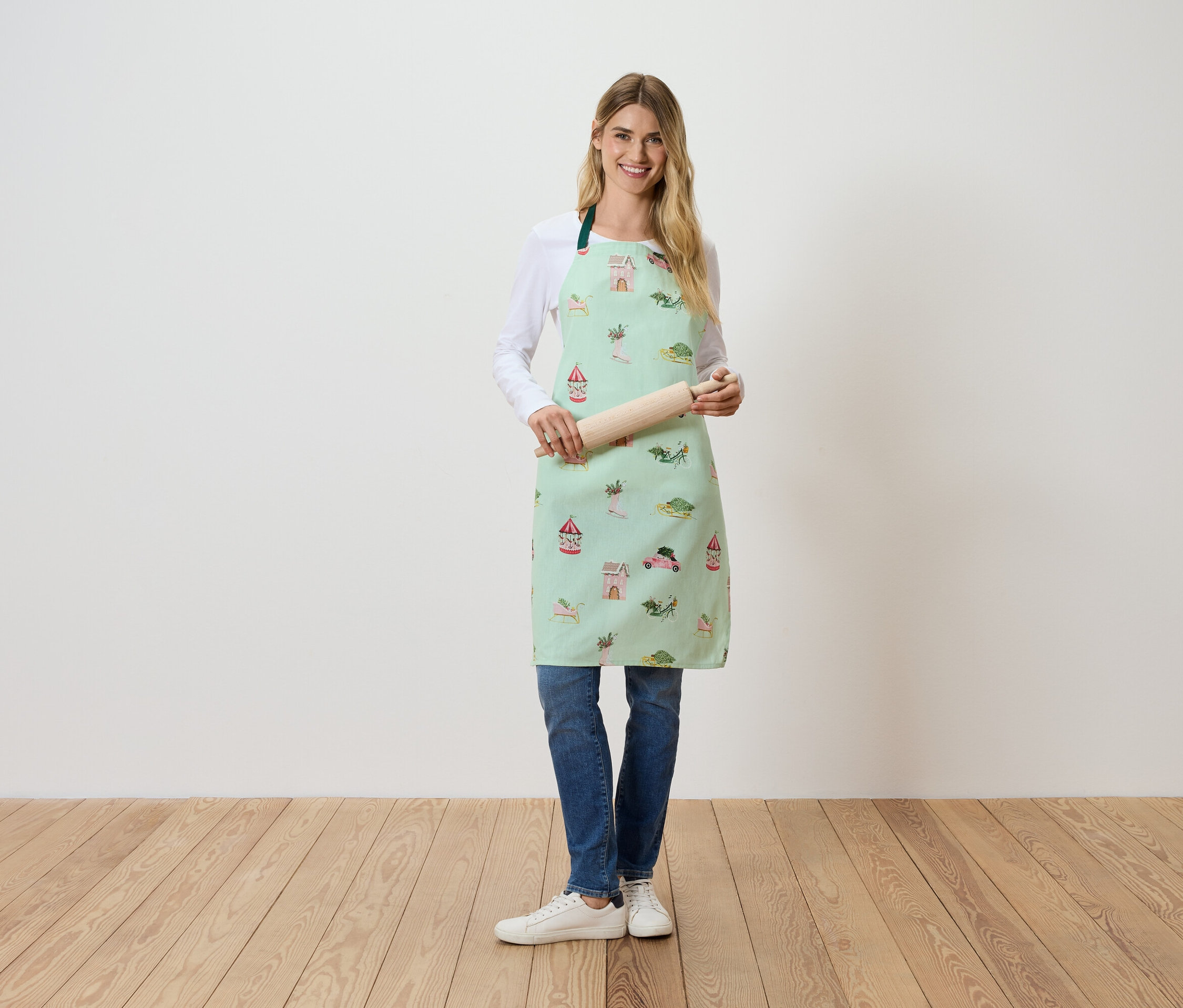 Bir kadın ayakta duruyor ve bir hamur açma tahtası tutuyor. Açık yeşil, desenli bir önlük giyiyor.
