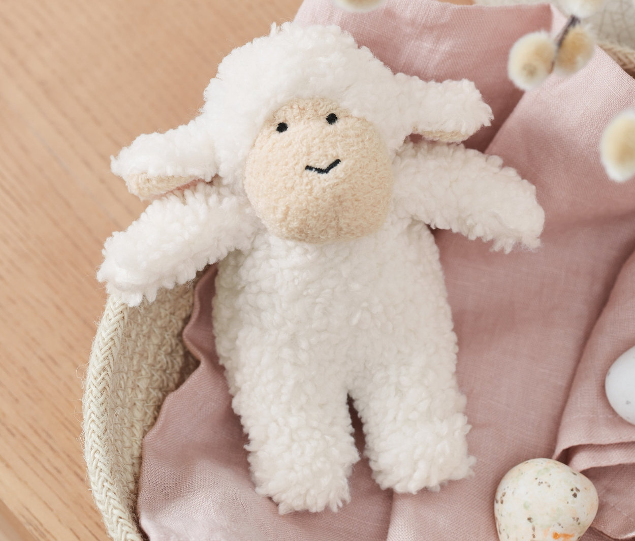 Sesli kuzu, söğüt dalları ve boyalı yumurtalarla dolu bir sepette duruyor.