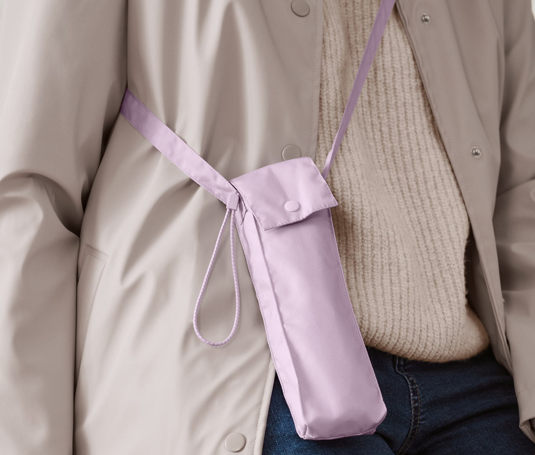 Bir kişi omuz askısıyla açık mor cep şemsiyesi taşıyor.