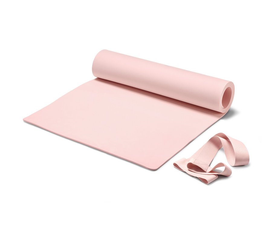 Beyaz bir arka plan üzerinde taşıma kayışı olan kısmen rulo halinde pembe Yoga ve Fitness Matı.