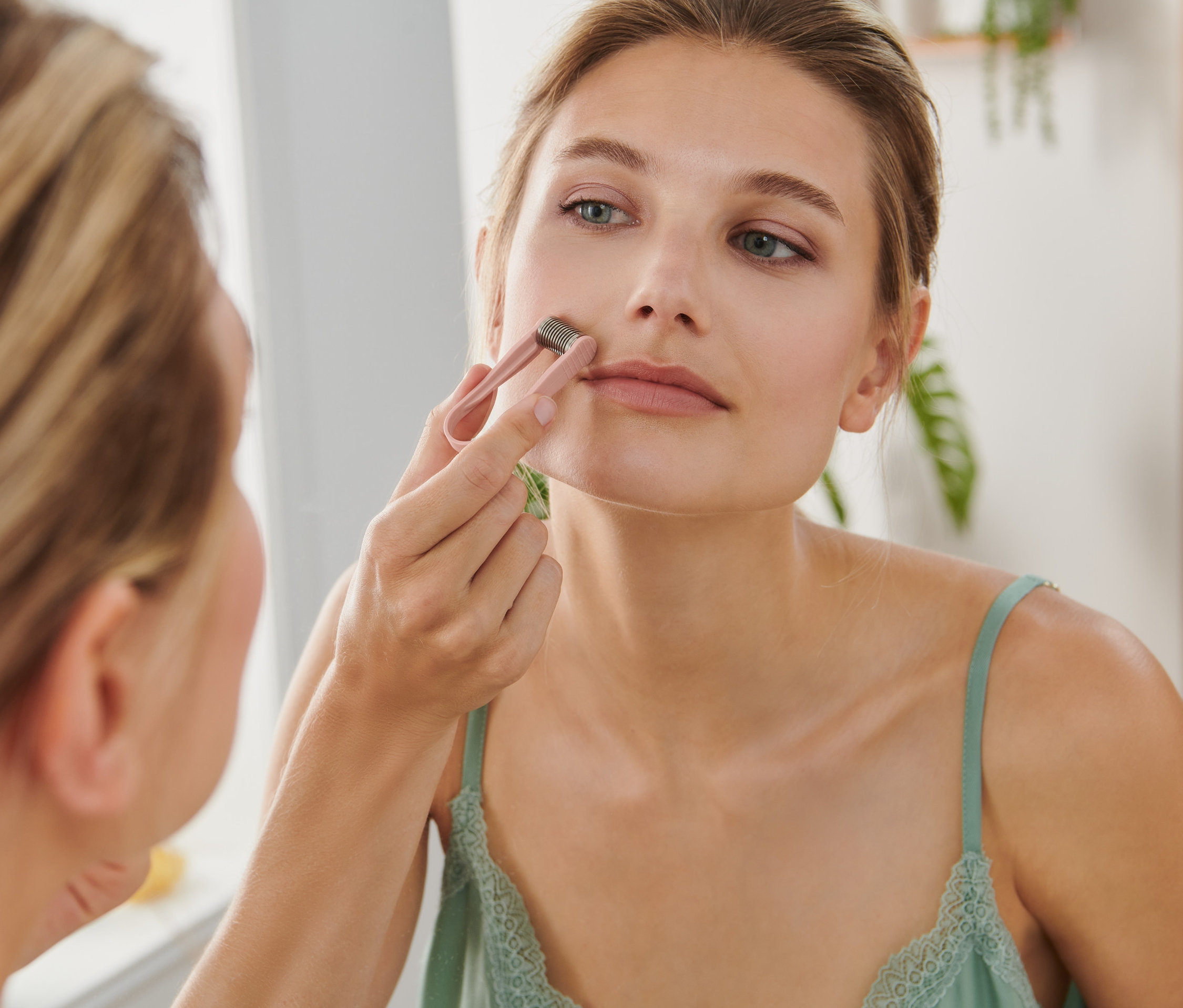 Kadın, üst dudağında mini yüz epilasyon aleti kullanıyor.