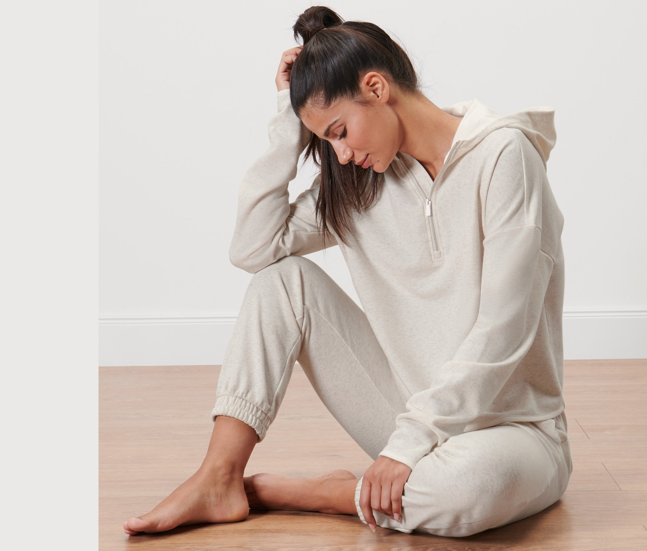 Kadın yerde oturuyor ve Sweat Kazak giyiyor.