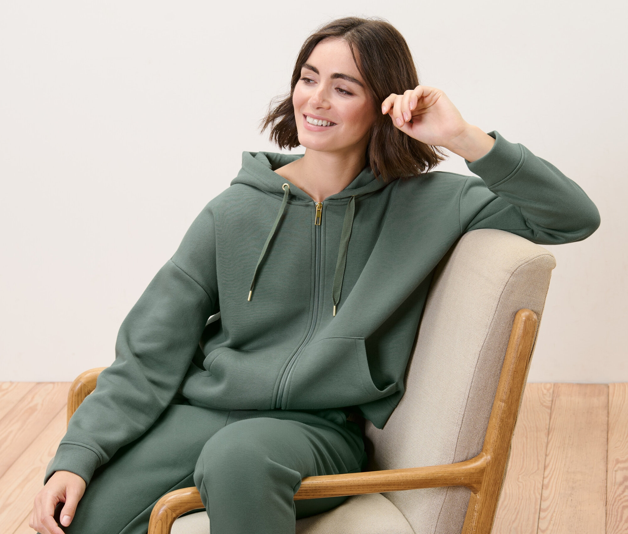 Kadın koltukta oturuyor ve Eşofman Üstü giyiyor.