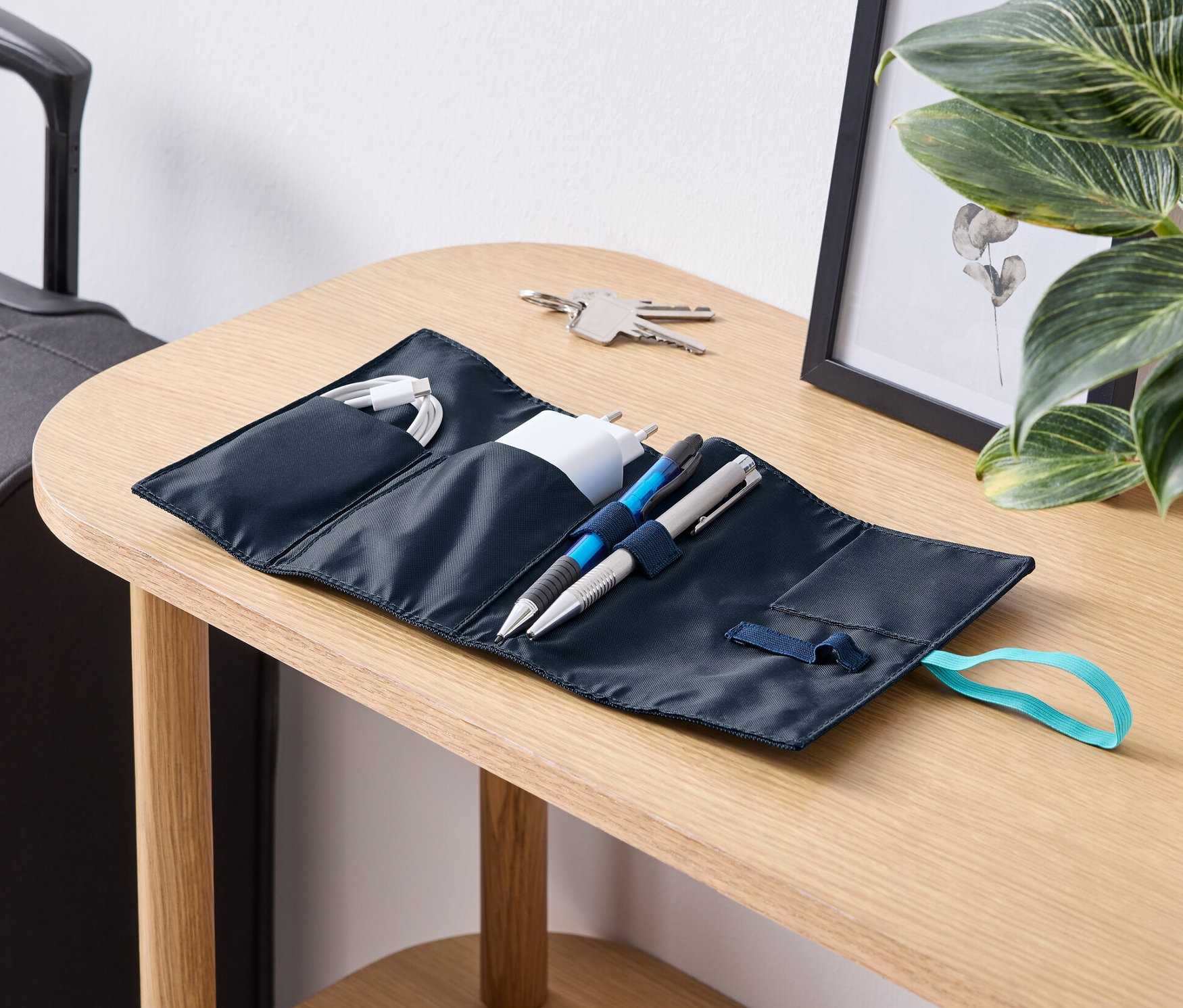 Bir masa üzerinde kablolar, şarj cihazı ve kalemlerle açık bir Yolculuk için Kablo Düzenleyici duruyor.