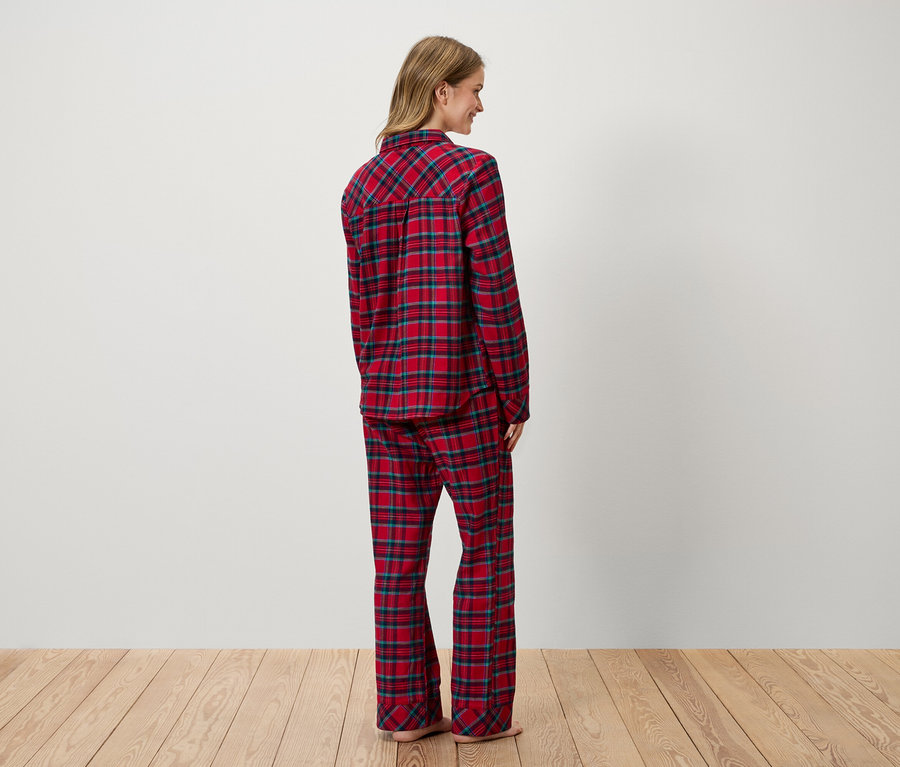 Kadın kameraya arkası dönük duruyor ve kırmızı ekose bir pijama giyiyor.