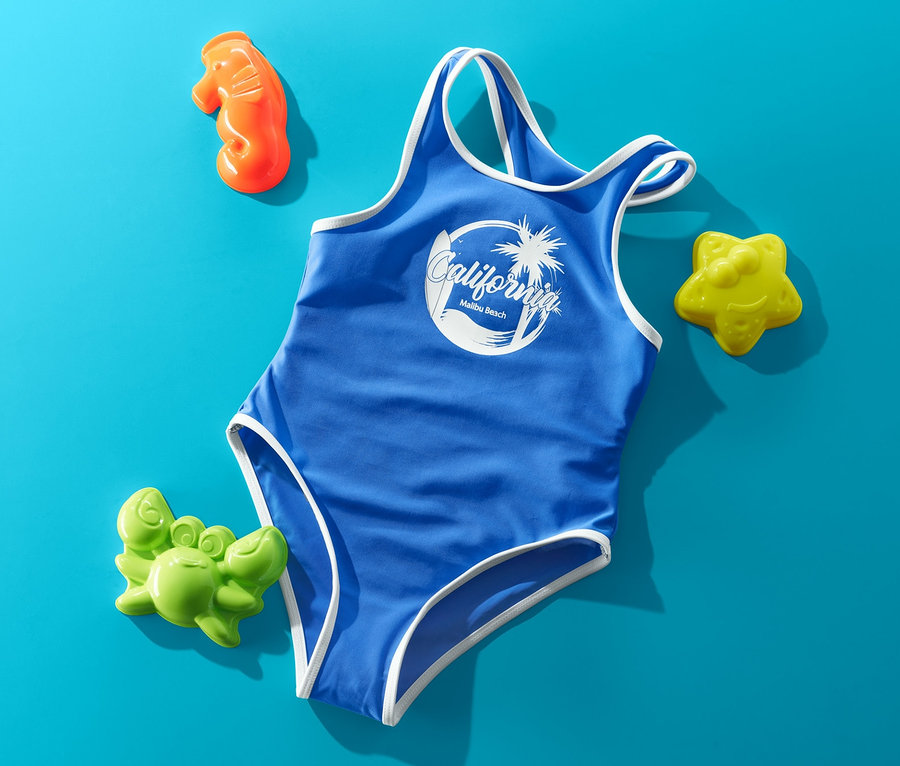 Mavi renkli, beyaz detaylı ve "California" baskılı mayo, mavi zemin üzerinde kum oyuncaklarıyla çevrili.