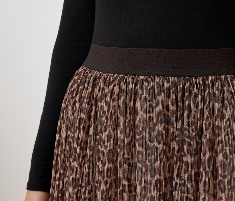Kahverengi leopar desenli kadın eteği ve uzun kollu siyah bir üstün yakın çekimi.