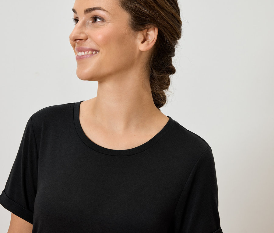 Siyah tişörtlü gülümseyen bir kadının portresi.