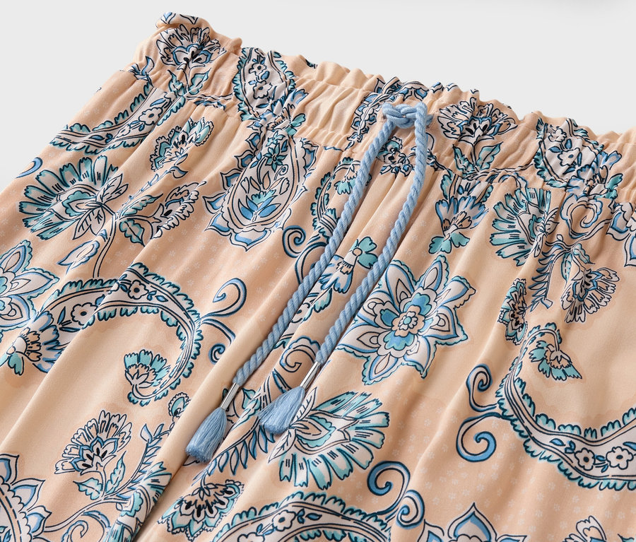 Şeftali rengi, mavi çiçek desenli ve ipli pantolonun yakın çekimi.