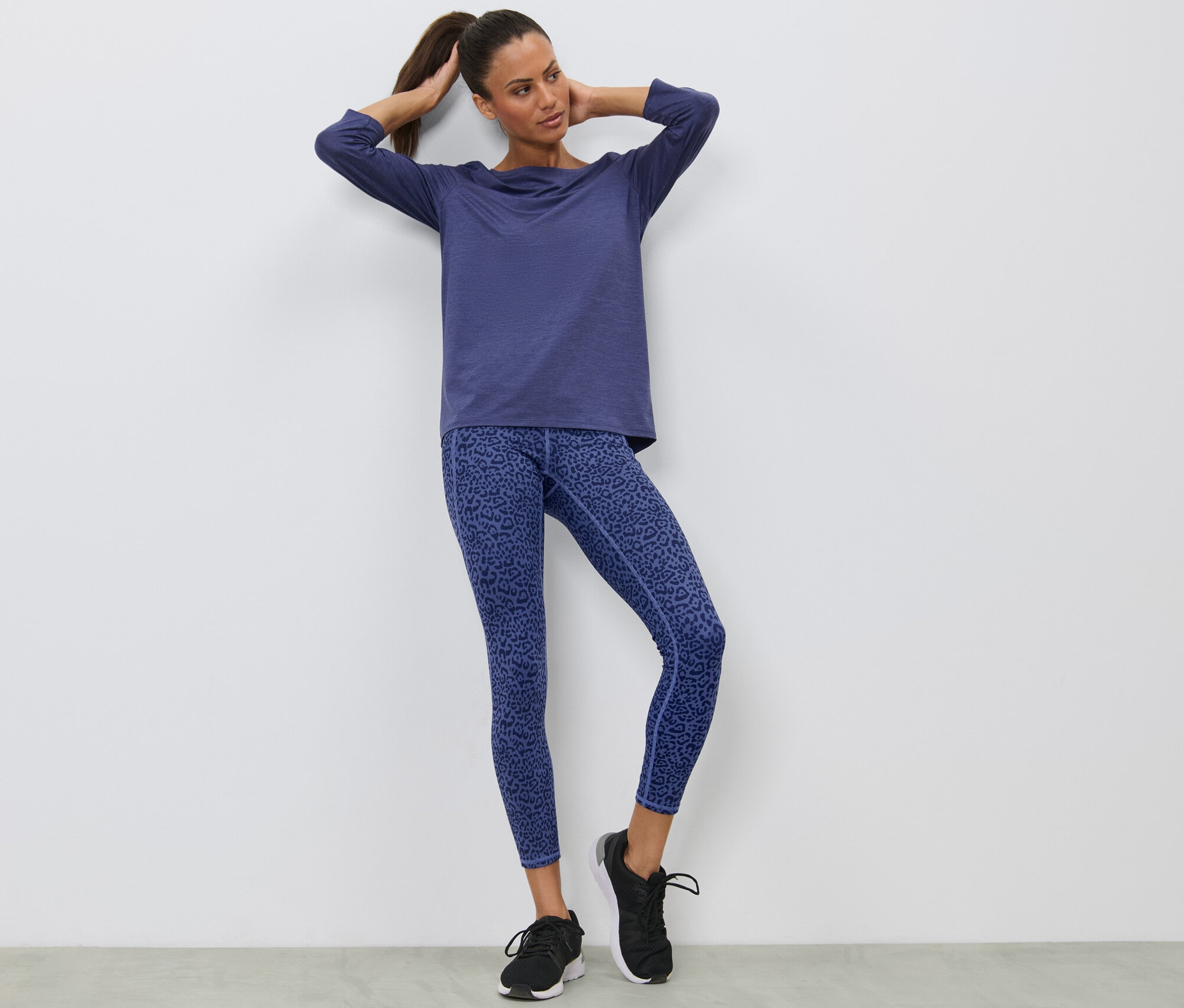 Kadın lila spor taytla poz veriyor.