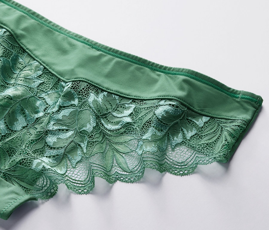 Beyaz bir arka plan üzerinde çiçekli dantel detayına sahip 4'lü yeşil Brazilian külotun yakın çekimi.