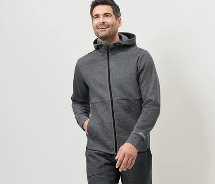 Adam, gri bir fonksiyonel sweat ceket giyiyor.
